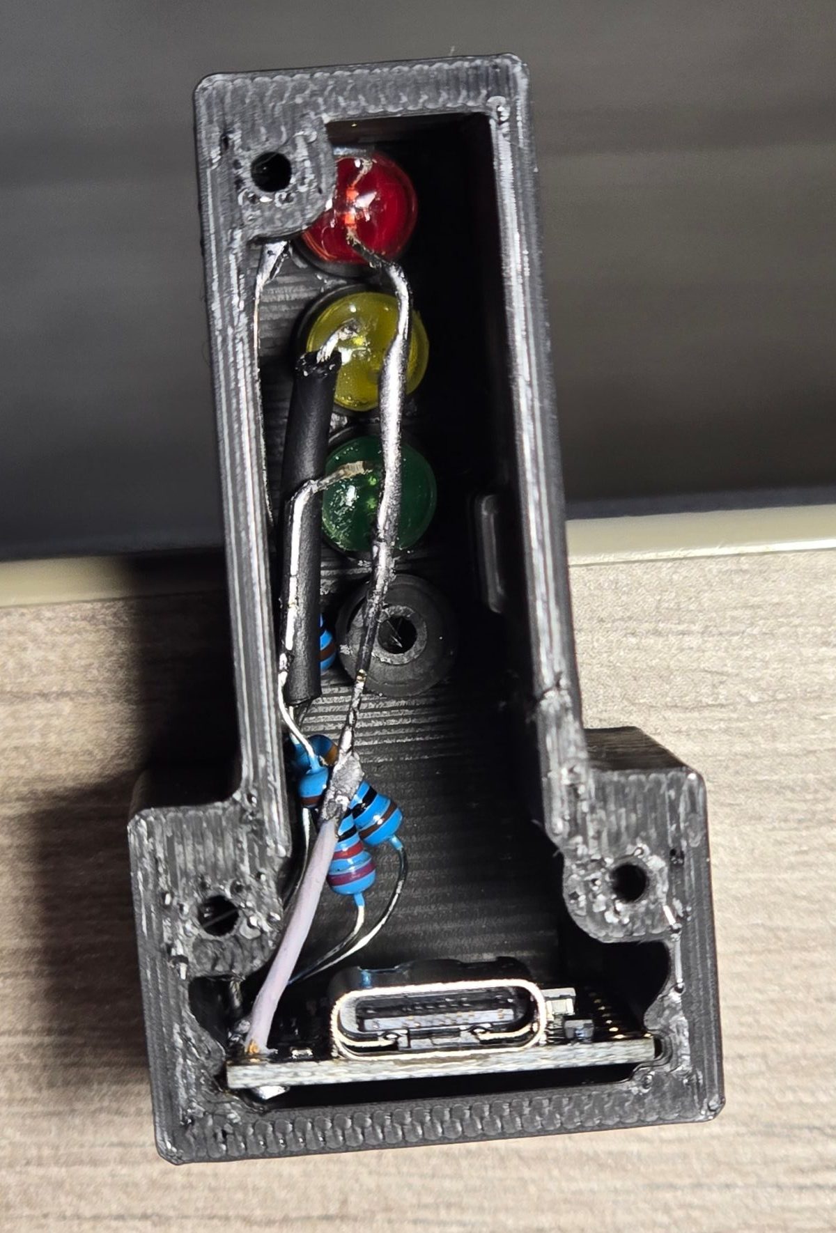 The built lamp from the rear with the cover and LED retainer removed: red, yellow and green LEDs from the top, each lead through its resistor, the shared ground lead running down to the ESP32-C3 SuperMini